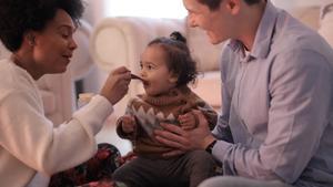 A couple spoon-feeding their child.