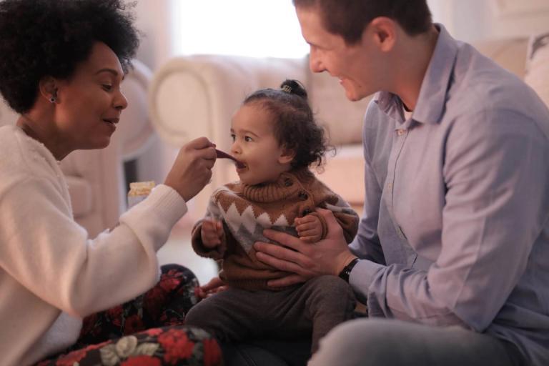 A couple spoon-feeding their child.