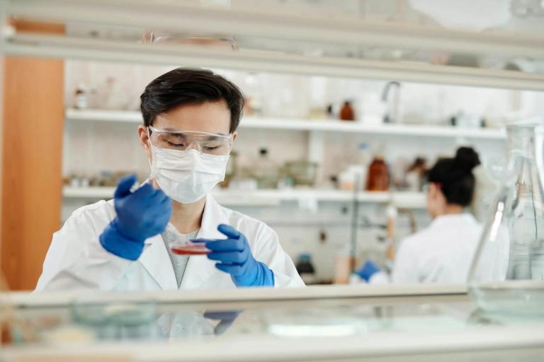 Lab worker drawing blood from a dish.