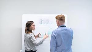 Two people brainstorming in front of a whiteboard.