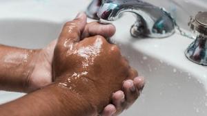 Close-up of hands being washed.