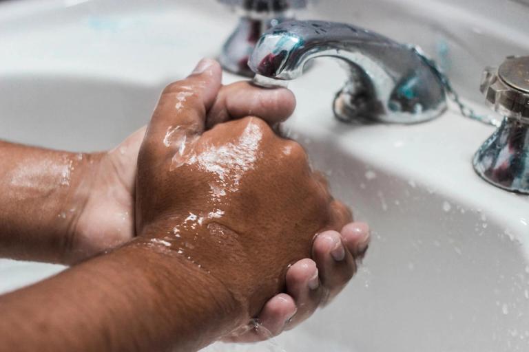 Close-up of hands being washed.