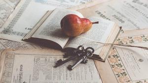 Open books with a pear and keys on a keychain.