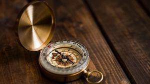 A golden compass on a wood table.