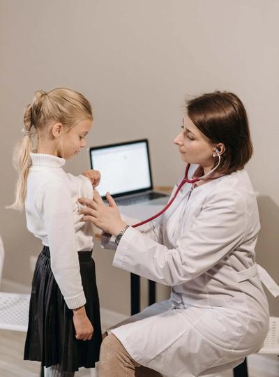 Doctor using a stethoscope on a young girl.