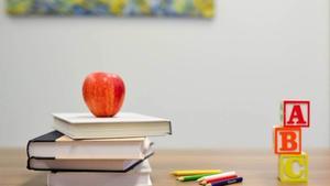 Stacked books, blocks, colored pencils, and an apple.